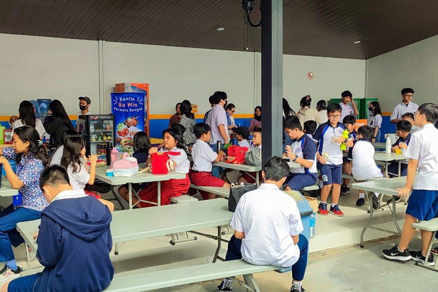 Happy students gathered at the Permata Bangsa School canteen, enjoying a culinary break, chatting, and relishing delicious meals, fostering a sense of community and camaraderie.